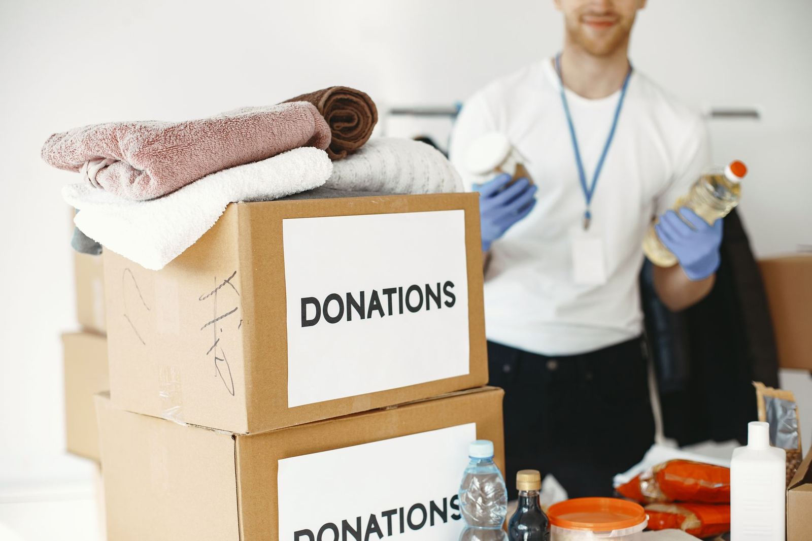 A volunteer sorting donation boxes beside a stack of folded blankets