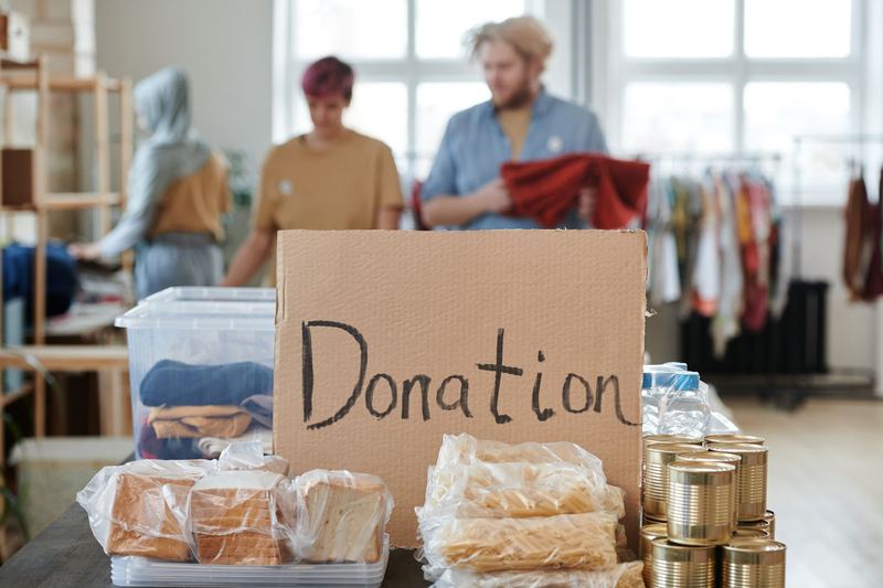 Volunteers behind a table of donated food and clothing
