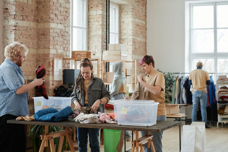 Volunteers sorting donated clothing at long tables in a shared space